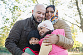 Portrait happy Muslim family hugging in autumn park