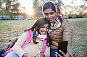 Muslim mother in hijab taking selfie with daughter