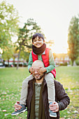 Portrait playful son riding on fathers shoulders