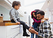 Father tying sons shoe in kitchen