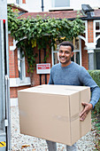 Portrait man moving house, carrying cardboard box