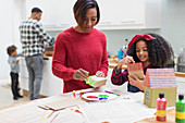 Mother and daughter painting house crafts in kitchen