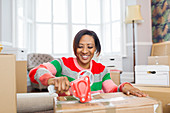 Smiling woman taping moving boxes, moving house