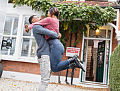 Happy, excited couple hugging outside new house