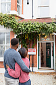 Happy couple hugging outside new house