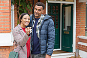 Portrait happy couple with house keys outside new house