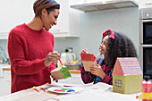 Mother and daughter painting house crafts in kitchen