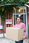 Woman moving house, carrying cardboard box