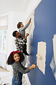 Portrait cute girl painting wall with father and brother