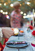 Woman lighting candles for dinner garden party