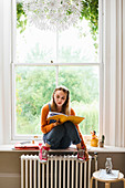 Focused young female college student studying in window