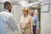 Doctor greeting senior couple in clinic doctors office