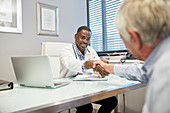 Male doctor shaking hands with senior patient