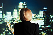 Businesswoman looking out at bright cityscape lights