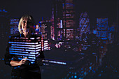 Businesswoman against highrise lights at night