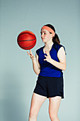 Teenage girl spinning basketball on finger