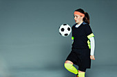 Teenage girl soccer player bouncing ball on knee