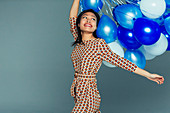 Carefree young woman with blue balloon bunch