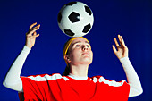 Teenage girl balancing soccer ball on head