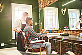 Male barber and customer with digital tablet talking