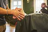 Male barber massaging face of customer in barbershop