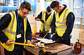 Male students using equipment in shop class workshop