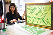 Female artist screen printing in studio