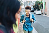 Laughing, happy young woman with backpack on sidewalk
