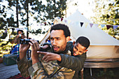 Curious father and son with binoculars at campsite