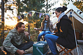 Happy friends playing cards at campsite in woods