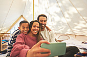 Happy family taking selfie in camping yurt