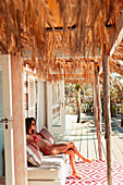 Young woman relaxing on beach hut patio