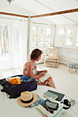 Woman writing in journal next to suitcase