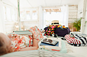 Woman with book relaxing on bed next to suitcase