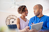 Couple talking, using digital tablet