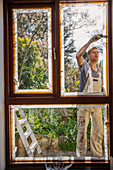 Male painter painting home exterior window trim