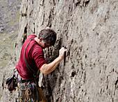 Male rock climber scaling rock face