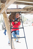 Grandfather playing with grandson on playground ladder
