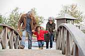 Grandparents walking with grandson on footbridge