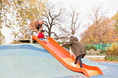 Grandparents playing with grandson on playground slide