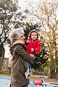 Grandmother carrying grandson at autumn playground
