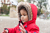 Cute, playful toddler boy playing with bubbles