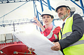 Dock worker and manager with blueprint talking at shipyard