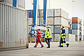 Dock workers walking along cargo containers at shipyard