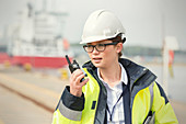 Female dock worker with walkie-talkie at shipyard