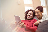 Happy couple using digital tablet on sofa