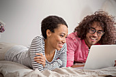 Smiling couple using laptop on bed