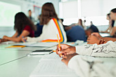 Student studying, writing in notebook during lesson