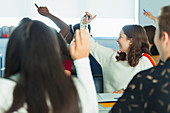 High school students with hands raised in classroom