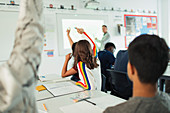 Students with hands raised during lesson in classroom